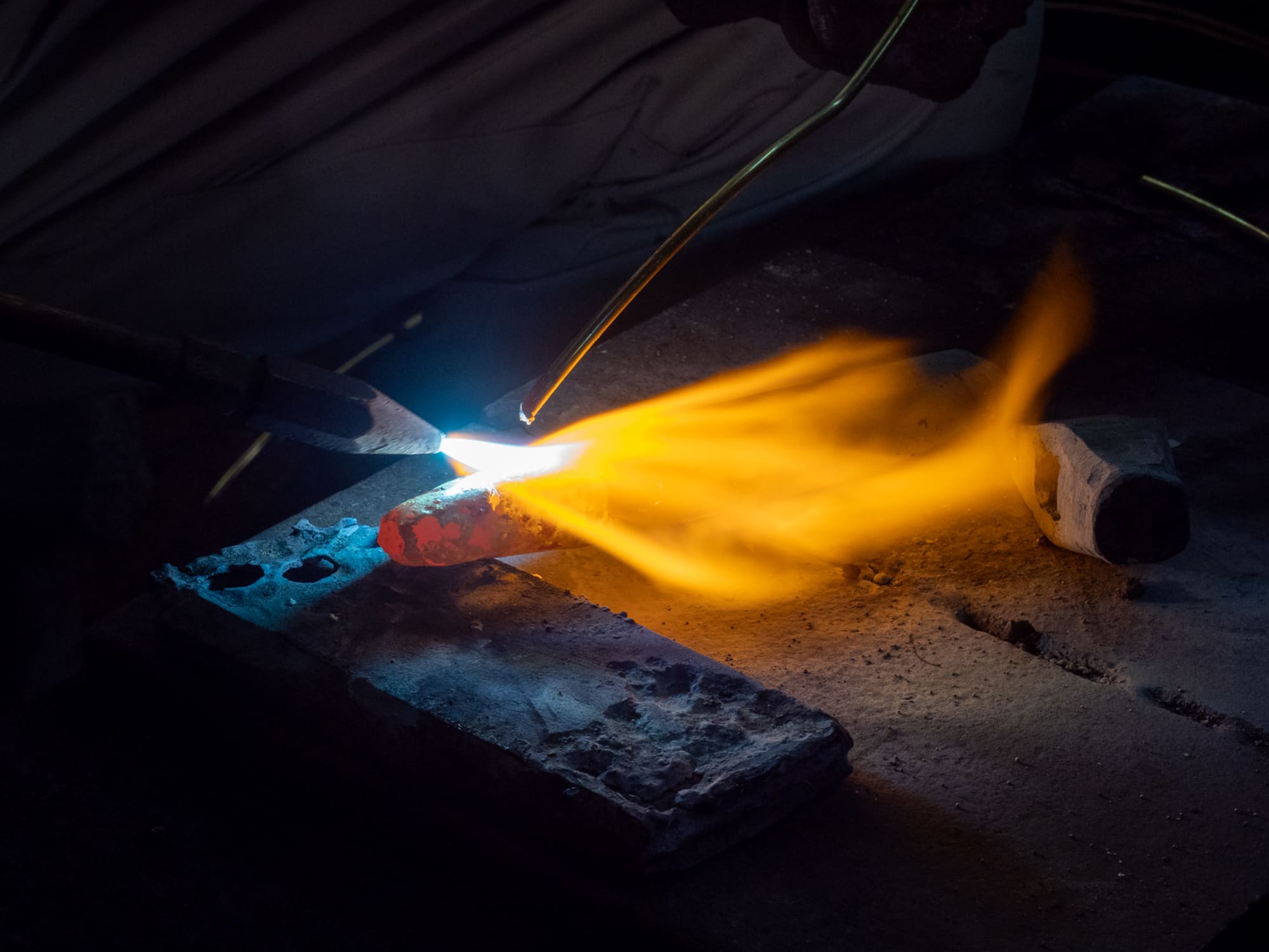 Kondo Stonemason Tools Factory brass brazing process by Yoji Kondo in Okazaki Japan - close up of blacksmith using torch flame to bond tungsten carbide tip onto steel chisel body
